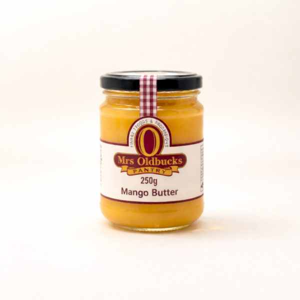 Mrs Oldbucks Pantry Mango Butter 250g jar of Mrs Oldbucks Pantry Mango Butter on a warm ivory background, showing smooth golden mango butter in a clear glass jar with black lid and burgundy label.