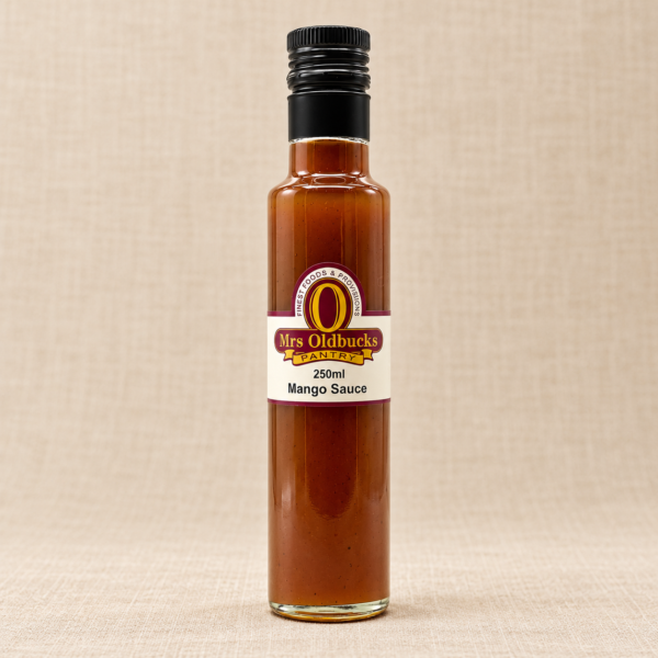 Mrs Oldbucks Pantry Mango Sauce 250 ml glass bottle with a black screw cap on a warm beige linen background.