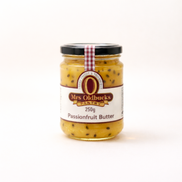 Mrs Oldbucks Pantry Passionfruit Butter250g jar of Mrs Oldbucks Pantry Passionfruit Butter on a warm ivory background, showing smooth golden passionfruit butter in a clear glass jar with black lid and burgundy label.