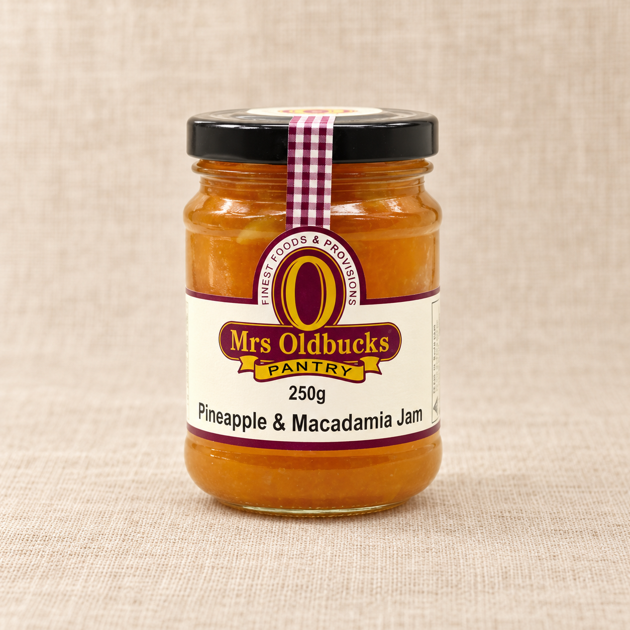 Mrs Oldbucks Pantry Pineapple and Macadamia Jam 250g jar on a warm beige linen background