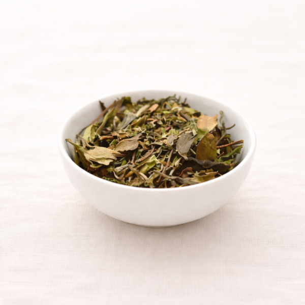 Mrs Oldbucks Pantry Pai Mu Tan white tea leaves with silvery buds in a white ceramic bowl on neutral linen in soft natural light.