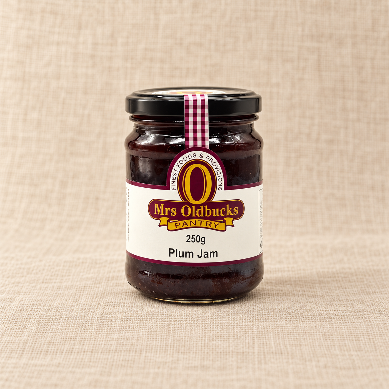 Mrs Oldbucks Pantry Plum Jam 250g jar on a warm beige linen background