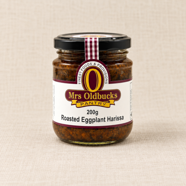 Mrs Oldbucks Pantry Roasted Eggplant Harissa 200g jar on a warm beige linen background.