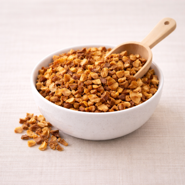 Mrs Oldbucks Pantry Turkish Apple loose leaf fruit tea in a white ceramic bowl on warm neutral linen, with golden apple pieces visible and a light wooden scoop resting in the blend under soft top-left lighting.
