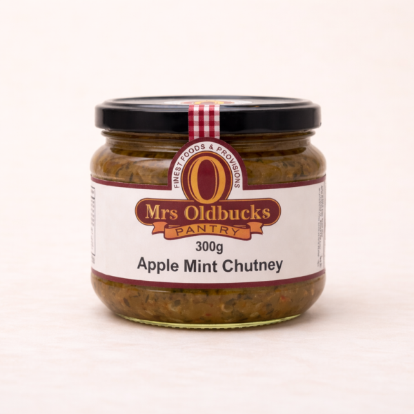 Mrs Oldbucks Pantry Apple Mint Chutney 300g jar of Mrs Oldbucks Pantry Apple & Mint Chutney on a warm ivory background, showing textured green chutney in a clear glass jar with black lid and burgundy label.