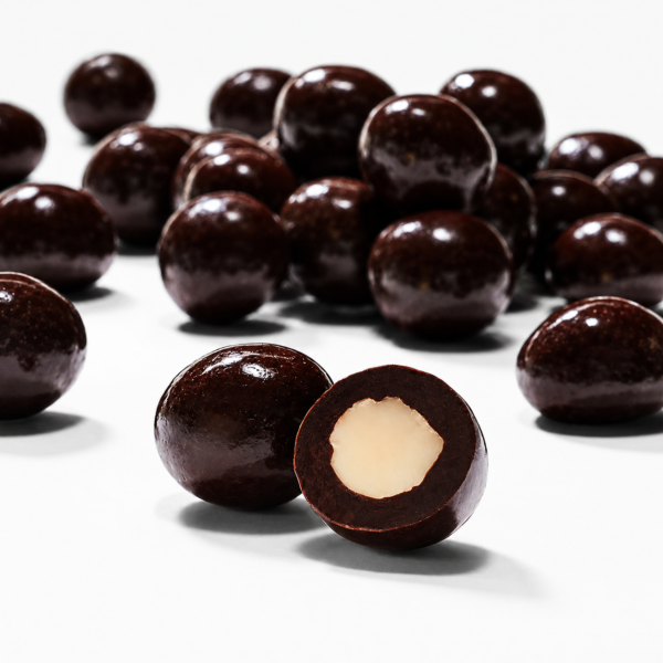 Mrs Oldbucks Pantry Dark Chocolate Macadamias Glossy dark chocolate-coated macadamia nuts arranged on a clean neutral background, featuring one cut open to reveal the creamy macadamia centre in a square WooCommerce product image