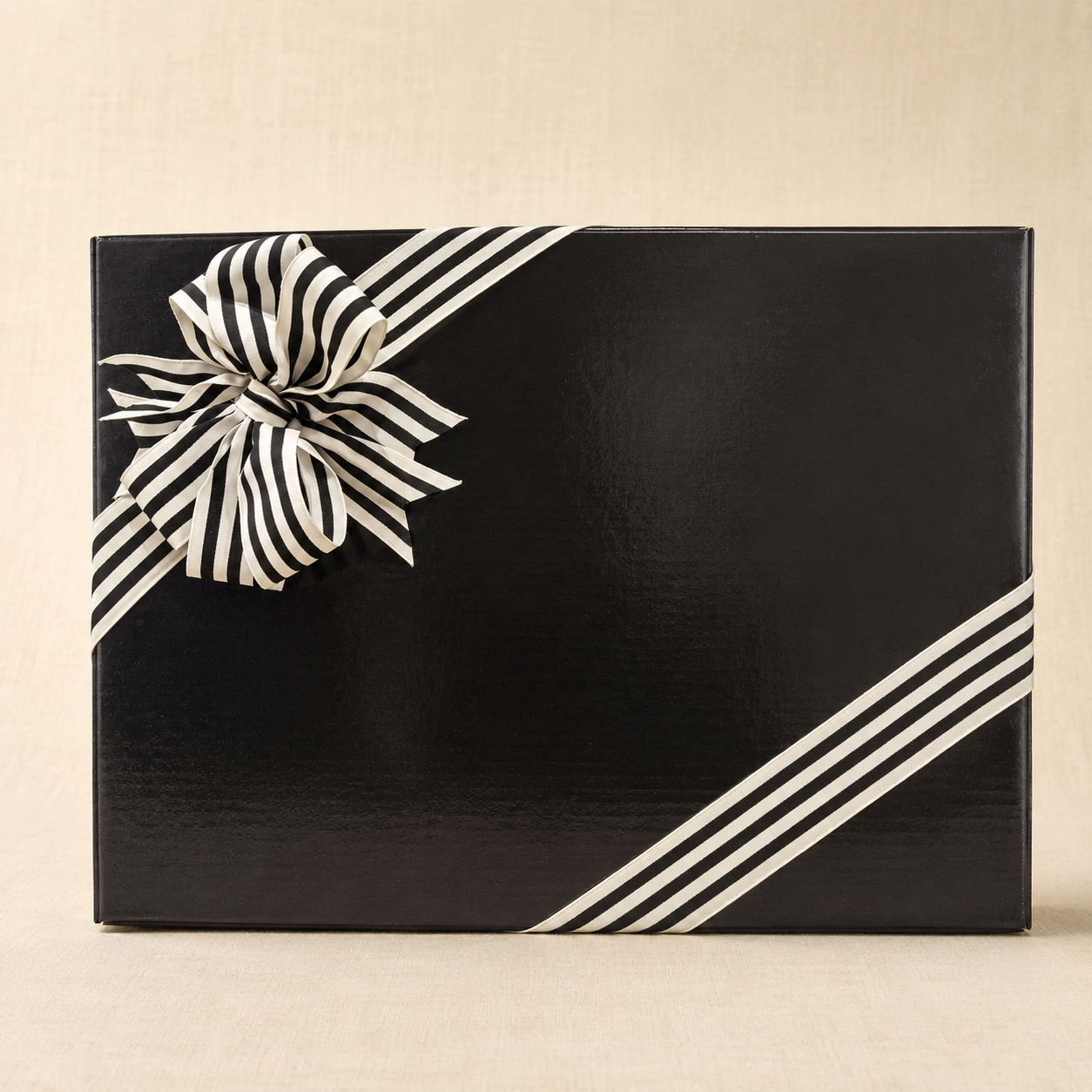 Black bespoke hamper gift box finished with black-and-ivory striped ribbon on a soft linen background